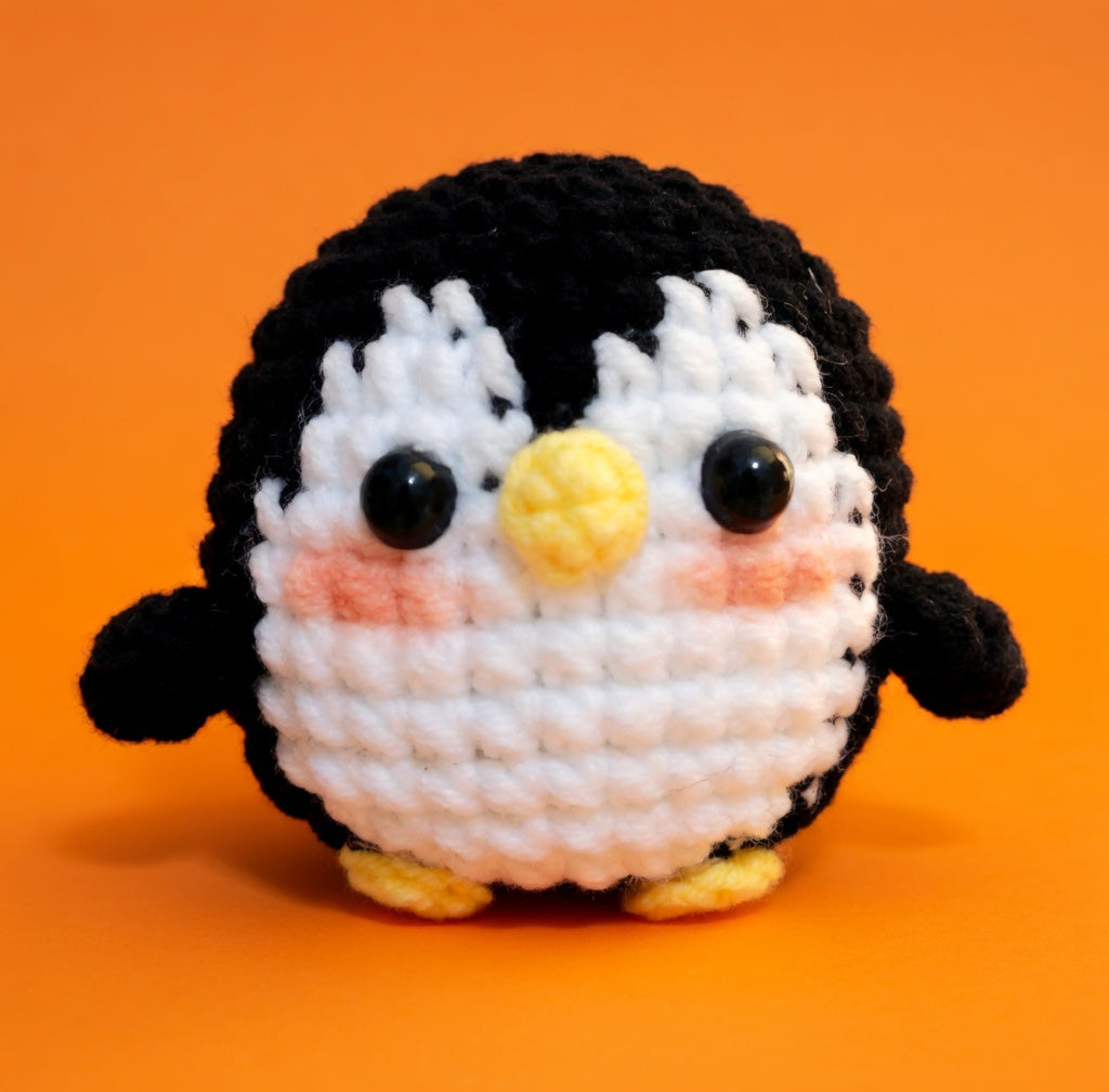 Crocheted penguin toy on an orange background
